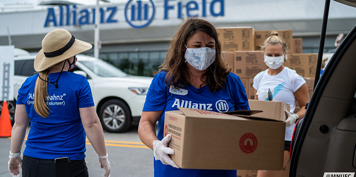 Allianz employee distributing box of food at farmer’s market
